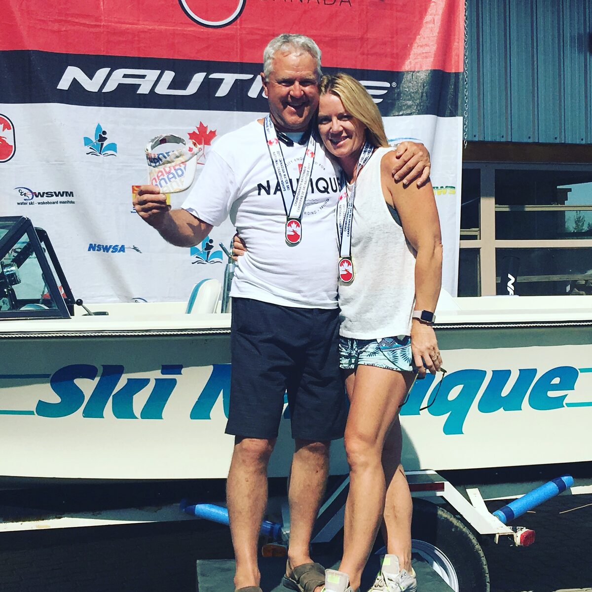 Ken Nelson and Kristy Kraus with medals at a Canadian waterski competition, Nautique boat behind them